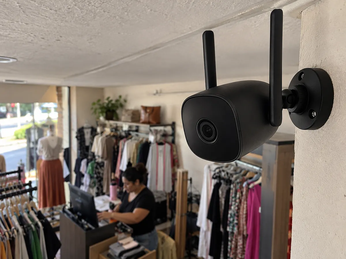 Câmera branca pequena no alto de uma prateleira de uma loja de roupas fechada